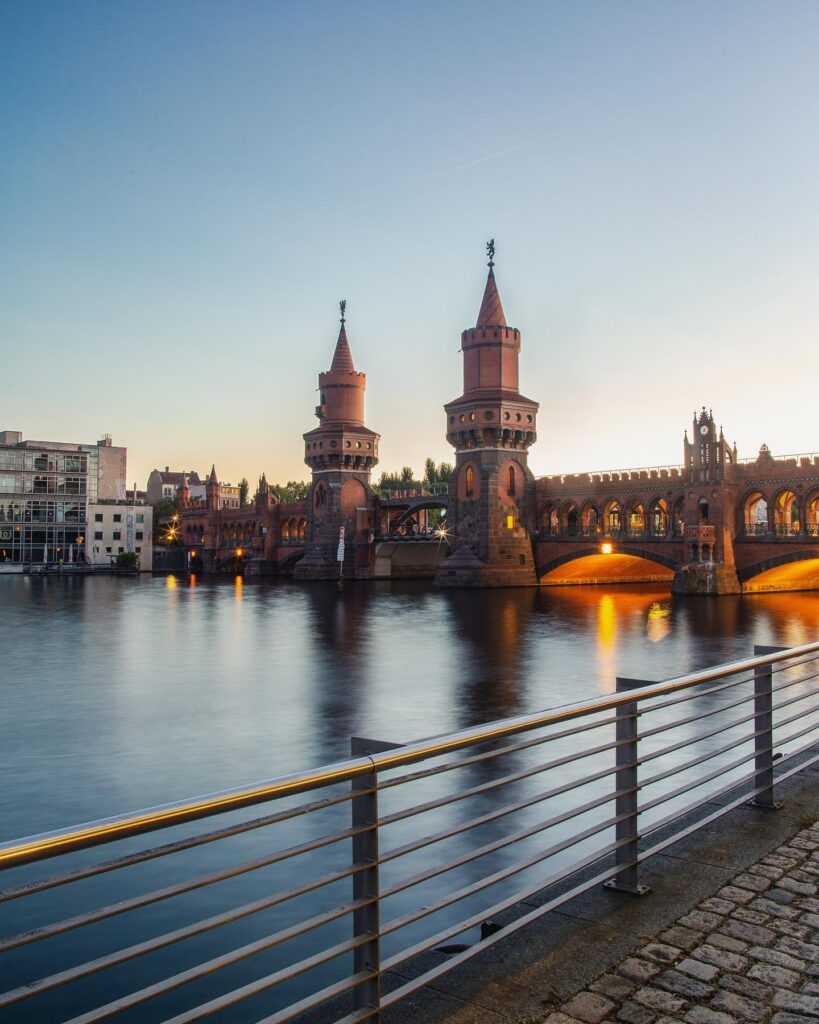 Oberbaumbrücke in Berlin bei Abendlicht, mit beleuchteten Bögen und ruhiger Wasseroberfläche der Spree.