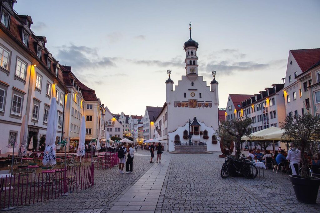 Abendstimmung in der Altstadt von Kempten mit beleuchtetem Rathaus, historischen Häusern und Außengastronomie.
