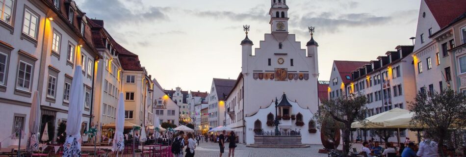 Abendstimmung in der Altstadt von Kempten mit beleuchtetem Rathaus, historischen Häusern und Außengastronomie.