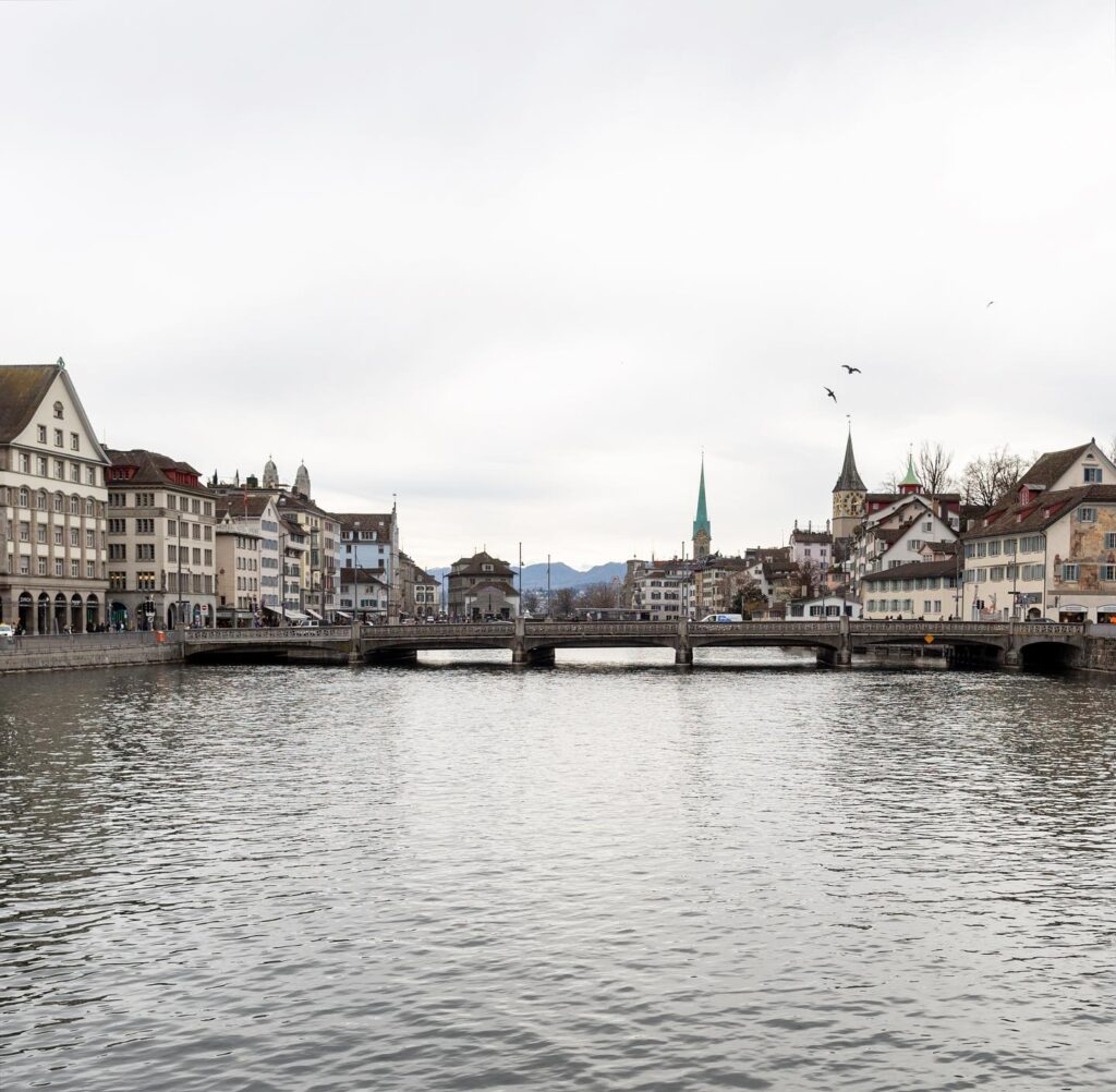 Blick auf Zürichs Altstadt mit Limmat, historischen Häusern und Kirchtürmen unter grauem Winterhimmel.